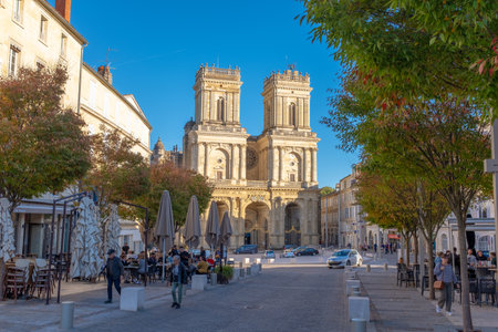 Auch, France - November 5, 2022: The Auch Cathedral steeples facing the sunset with some people sitting and walking on a busy commercial streetのeditorial素材