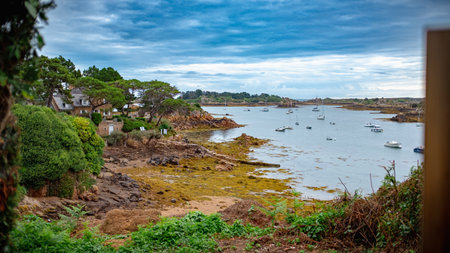 Stone houses overlooking a natural harbor occupied by some small sailboats. Taken on an overcast summer morning, Brehat Island, Brittany, France.の写真素材