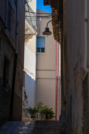 A narrow street of Scicli, Sicily, Italy mostly in shade. Taken on a sunny winter day with no peopleの写真素材