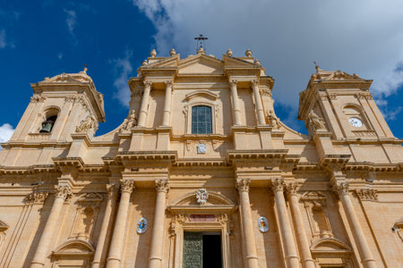Low angle view of the facade of the San Nicolo cathedral, Noto, Sicily, Italy. Taken under a sunny sky with clouds and with no people.の写真素材