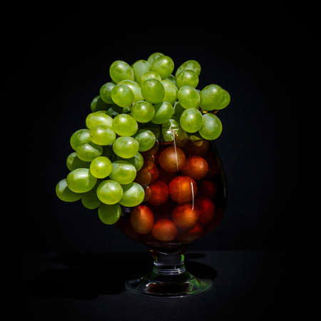 bunch of green grapes in a glass goblet on a dark backgroundの写真素材