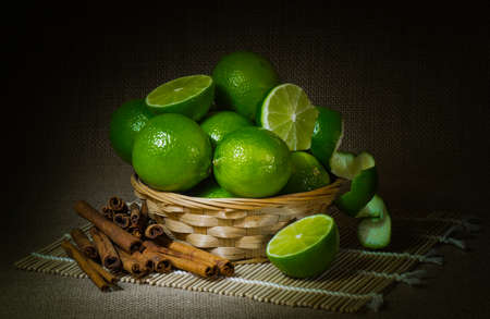 still life; lime fruit in wicker Cup, cinnamon, dark backgroundの写真素材