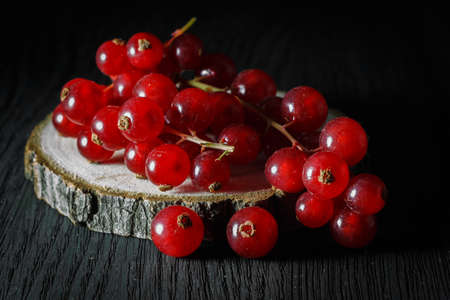 red currant on a wooden die, dark backgroundの写真素材