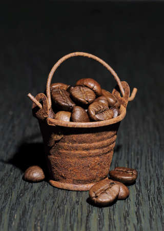 coffee beans in a small rusty bucket on a dark backgrounの写真素材