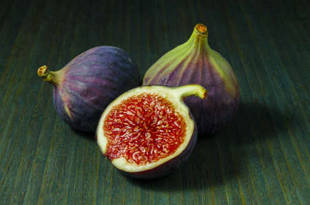 figs, whole and half on green wooden backgroundの写真素材
