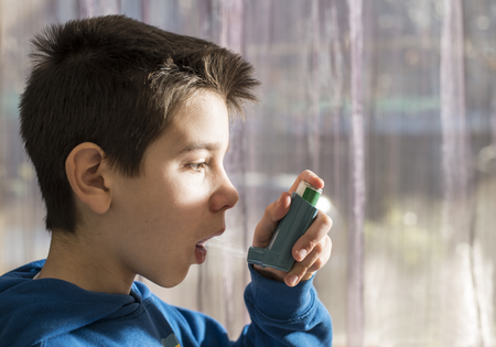 Child holds an inhaler. Close up boy to the windowの写真素材