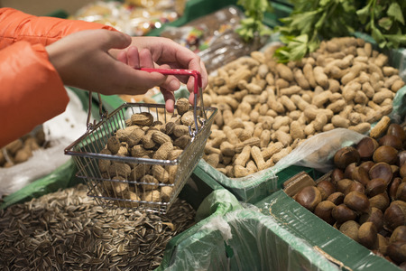 Fruits in supermarket. Buying peanuts in shop. Small basket.の写真素材