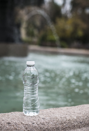 Bottle mineral water and fountain on the backgroundの写真素材