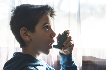 Child holds an inhaler. Close up boy to the windowの写真素材