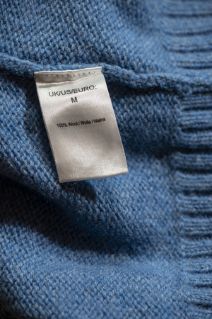 Label with instructions for washing inside on blue woolen sweater.