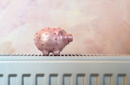 Pink shiny piggy money box on heater in home. Pink Wall backgroundの写真素材