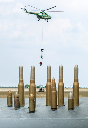 Soldiers on a rescue military operation with helicopter. War and conflict concept showing military exercises. Cartridges and ammunition in the foreground.の写真素材