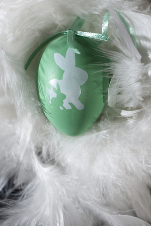 Green and white eggs on feather background. Easter conception with shape of rabbits on eggs.の写真素材