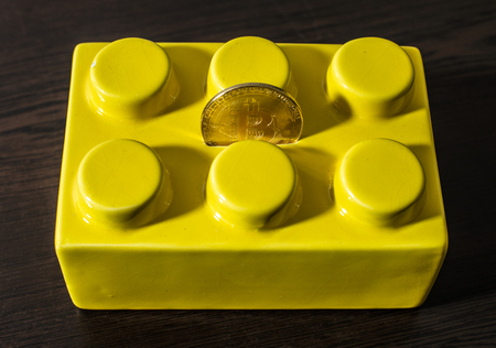 Yellow Money box and bitcoin coin on top. Savings and crypto currencies conception. Dark background. Room ambient light.の写真素材