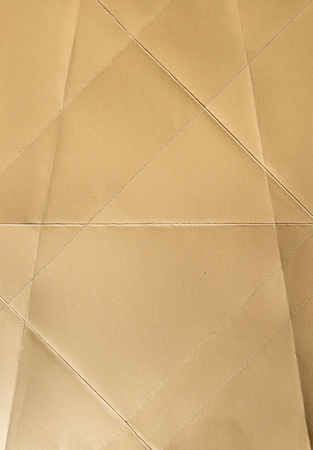 Folded orange pantone color paper. Pastel tones. Hard natural light. Folds and wrinkles on paper. Geometric shapes and figures on the paper.の写真素材