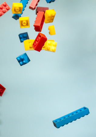 Floating Plastic geometric cubes in the air. Construction toys on geometric shapes falling down in motion.  Blue pastel background. Children's toys. Circle geometric shapes on plastic bricks.の写真素材