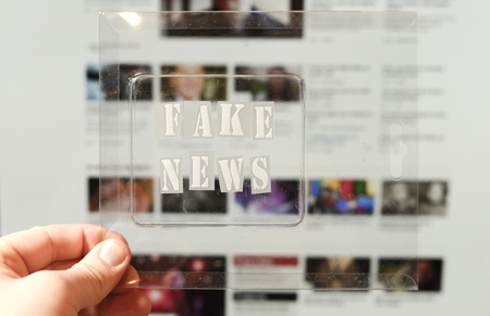 Fake news text and website on the background. Fake news conception with transparent words. Blurred Images and articles on background.の写真素材