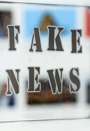 Fake news text and website on the background. Fake news conception with transparent words. Blurred Images and articles on background.の写真素材