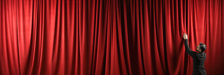 A hand reaching out from behind a red curtain in theatre.の素材
