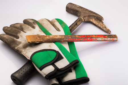 Assortment of work gloves with green stripe on top of broken mallet and rusted crowbarの写真素材