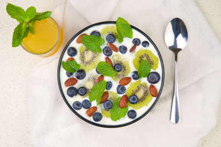 Natural and organic yogurt bowl with blueberries, kiwi slices and almonds on a white background. Top view.の写真素材