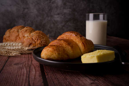Loaf of bread on woDelicious breakfast croissant with butter on a wooden table with glass milk and bread as background.oden board. Breakfast on wooden table with grey concrete background.の写真素材