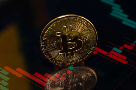 Golden Bitcoin token with candlestick chart background. Digital currency. Cryptocurrencyの写真素材