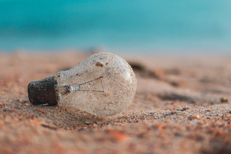 Glass light bulb pollution on the beach. Environmental Pollution. Global Warming. Save Earth.