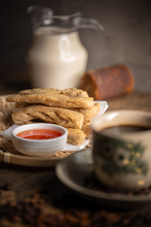 Keropok Lekor or Fried Fish Cake on a Rattan Plate with a Sweet Chilli Sauce and on Wooden Table....