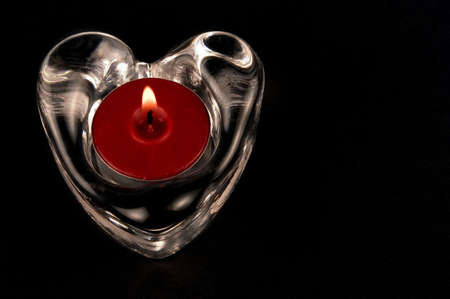 valentines heart in glass  with candle isolated one a black backgroundの写真素材