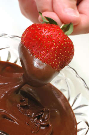 Strawberry being dipped in bowl of chocolate.の写真素材