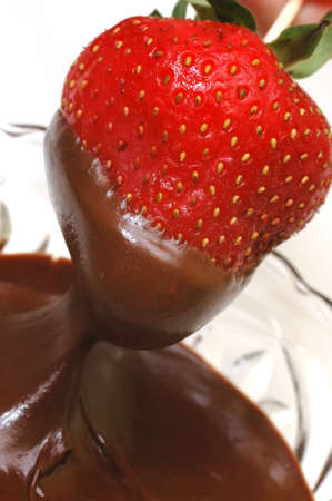 Strawberry being dipped in bowl of chocolate.の写真素材