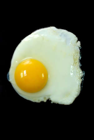 Egg cooked sunny side up isolated on black background.の写真素材
