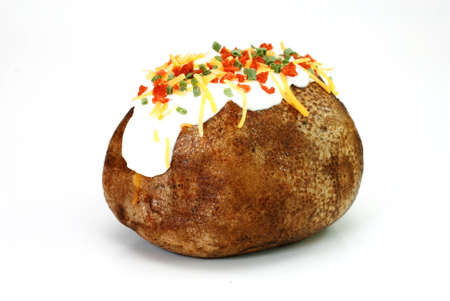 Baked potato loaded with butter, sour cream, cheddar cheese, bacon bits, and chives.  Isolated on white background.の写真素材