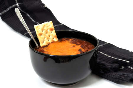Bowl of chili with melted cheese, cracker, spoon, and scarf.  Isolated on white background.の写真素材