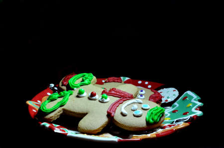 Gingerbread men on plate with candle on black background.の写真素材