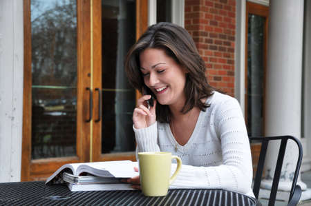 Female student studying while talking on cell phone.の写真素材