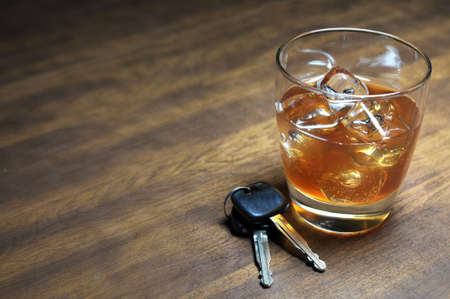 Glass of whiskey and car keys on wooden table.の写真素材