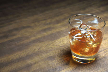 Bourbon on the rocks on wooden table with copy space.の写真素材