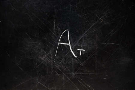 A+ grade on black chalkboard with copy space.  Chalk dust on board. の写真素材