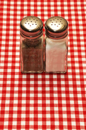 Salt and pepper shakers on red gingham tablecloth.の写真素材