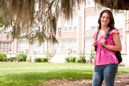 Female college student standing in front of school with backpack.  の写真素材