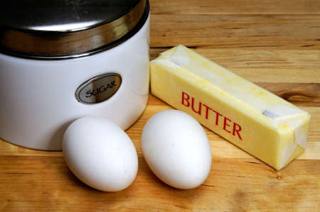 Eggs, butter, and sugar on cutting board.