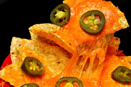 Closeup of nachos with jalapeno pepper slices.  Isolated on black background.の写真素材