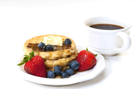 Waffles, strawberries, blueberries, and butter with cup of coffee.  Breakfast isolated on white background.の写真素材