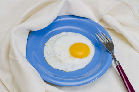 Fried egg on plate with fork and napkin.の写真素材