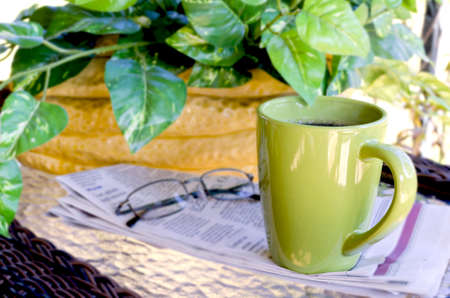 Morning coffee with newspaper and reading glasses   Green plant in background の写真素材