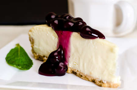 Slice of blueberry cheesecake and coffee with mint garnish.  Shallow depth of field.の写真素材