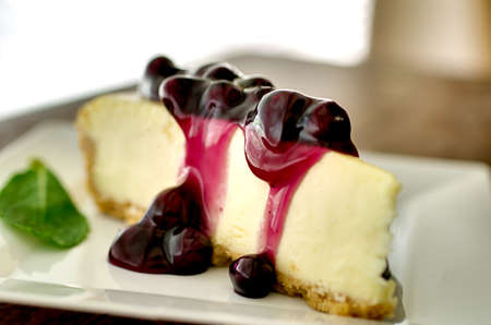 Slice of blueberry cheesecake in the afternoon with mint garnish.  Shallow depth of field.の写真素材