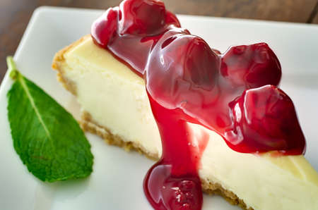 Closeup of cherries on cheesecake with mint garnish.   Shallow depth of field.  の写真素材